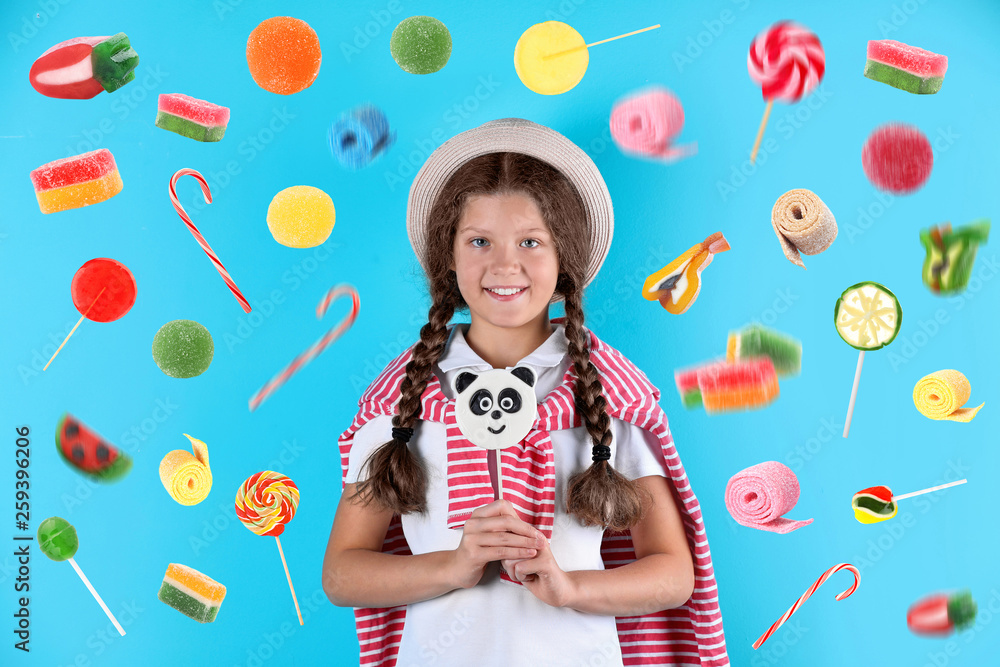 Little girl with candy on color background