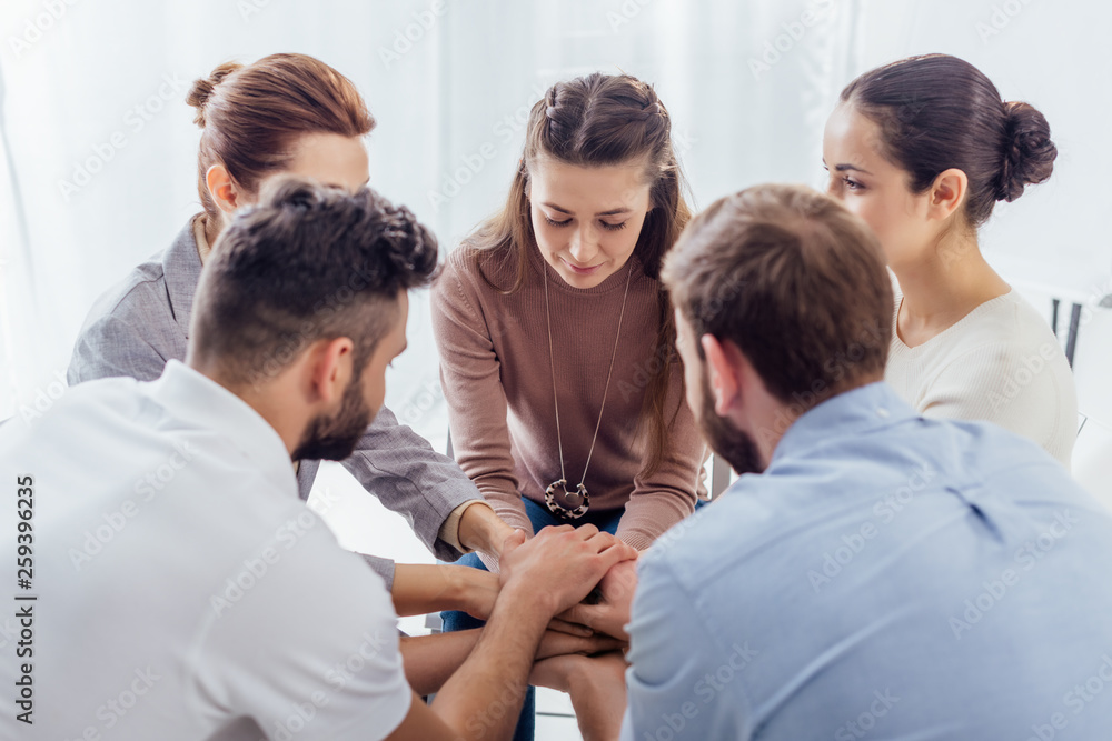 Fototapeta premium people sitting stacking hands during group therapy session