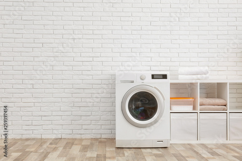 Vászonkép Modern washing machine near brick wall in laundry room interior, space for text