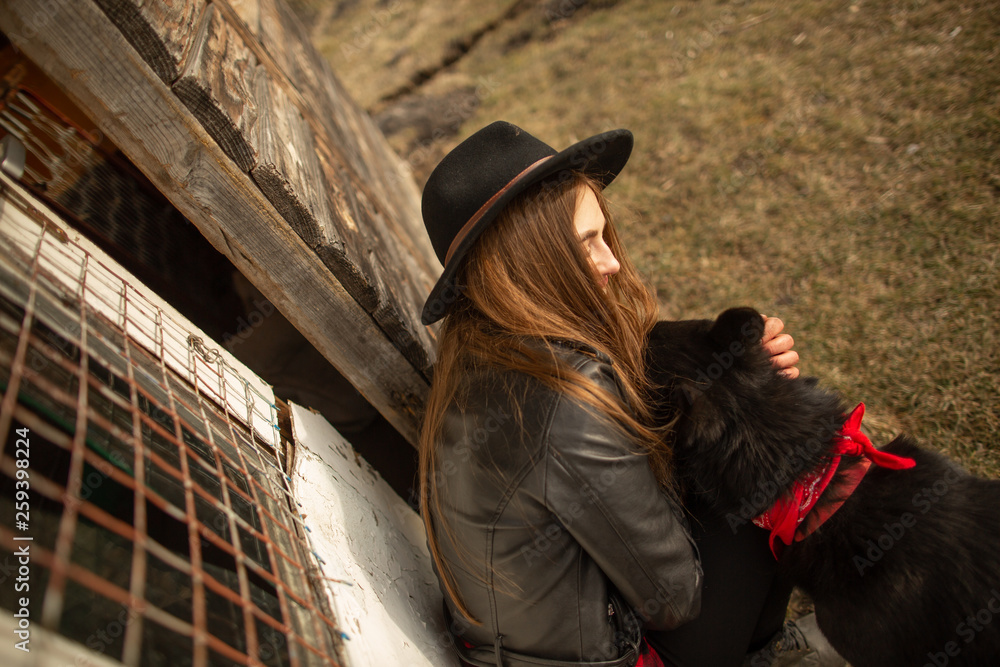 Happy young woman plaing with her black dog Brovko Vivchar in fron of old wooden house. Happy young woman plaing with her black dog Brovko Vivchar in fron of old wooden house.