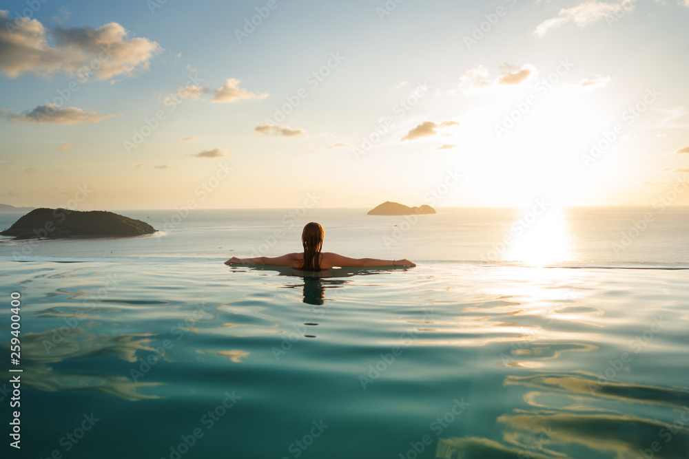 girl in the pool at sunset with views of the mountains and the sea