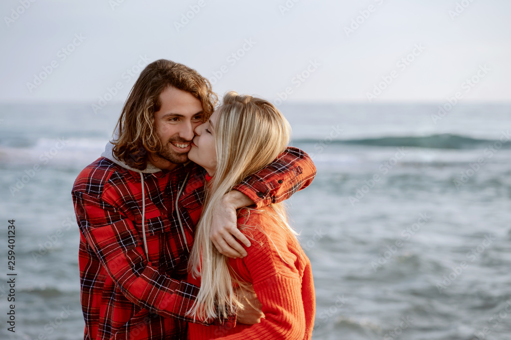 Girlfriend hugging and kissing handsome guy on beach. Holidays at sea on vacation. Portrait at sunset. Girlfriend hugging and kissing handsome guy on beach. Holidays at sea on vacation. Portrait at sunset.