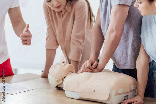 cropped view of man performing chest compression on dummy during cpr training class photo