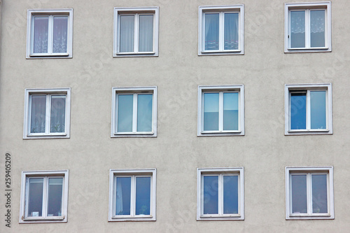 white plastic windows of an apartment building, symmetrical frames in a gray house. many rooms in one house. modern housing construction. old building