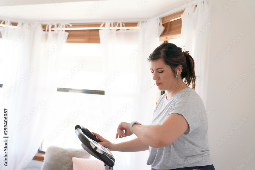 Woman checking time while exercising on stationary bicycle