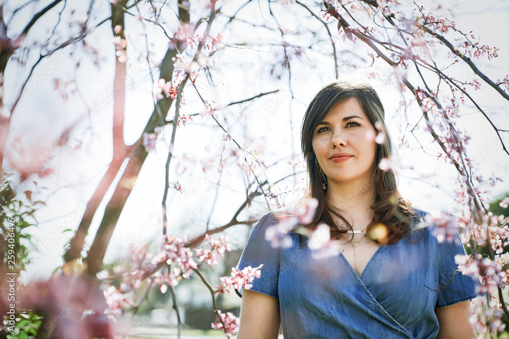 Brunette woman standing near cherry blossom tree Brunette woman standing near cherry blossom tree