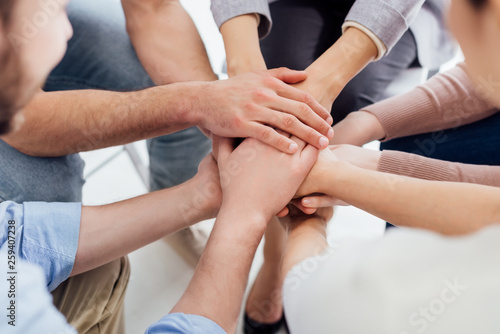 cropped view of people stacking hands during group therapy session