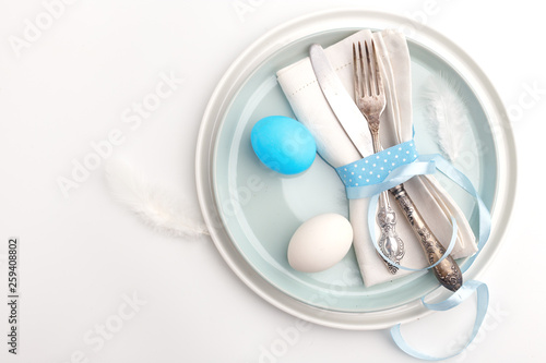 Elegant stylish table setting. Knife and fork on a napkin on a plate on a white background.