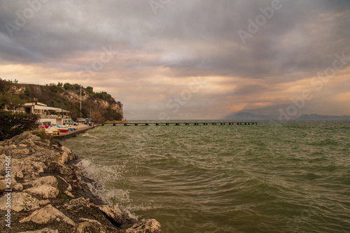 Scenic view of Lake Garda at sunset with a pier and a cliff in the background, Sirmione, Lombardy, Italy