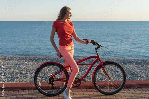 The blonde is riding a bike along the coast. Urban cycling