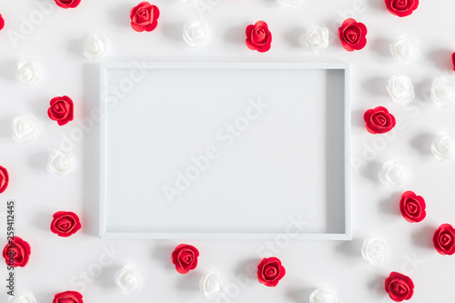Flowers composition creative. Blank photo frame, red and white artificial flowers on white background. Flat lay, top view, copy space  © prime1001