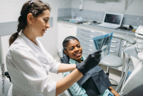 Female dentist shows x-ray picture to patient