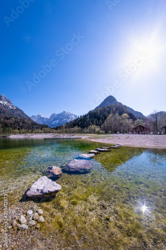 Rocks in lake Jasna with mountains Razor Prisojnik in Slovenia