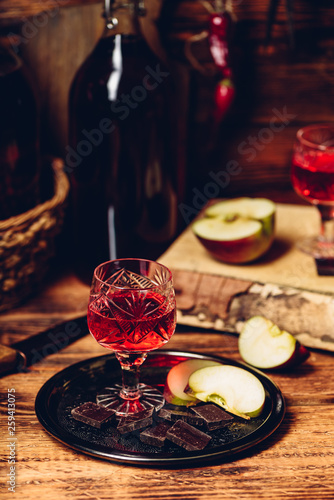 Glass of homemade redcurrant nalivka with apple slices and chocolate