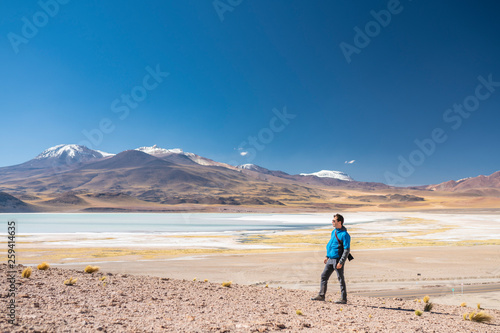 Landscape man photographer taking photos in an amazing wilderness environment at Atacama Desert Andes mountains lagoons. A man cut out silhouette over the awe Tuyajto Lagoon scenery at Altiplano 