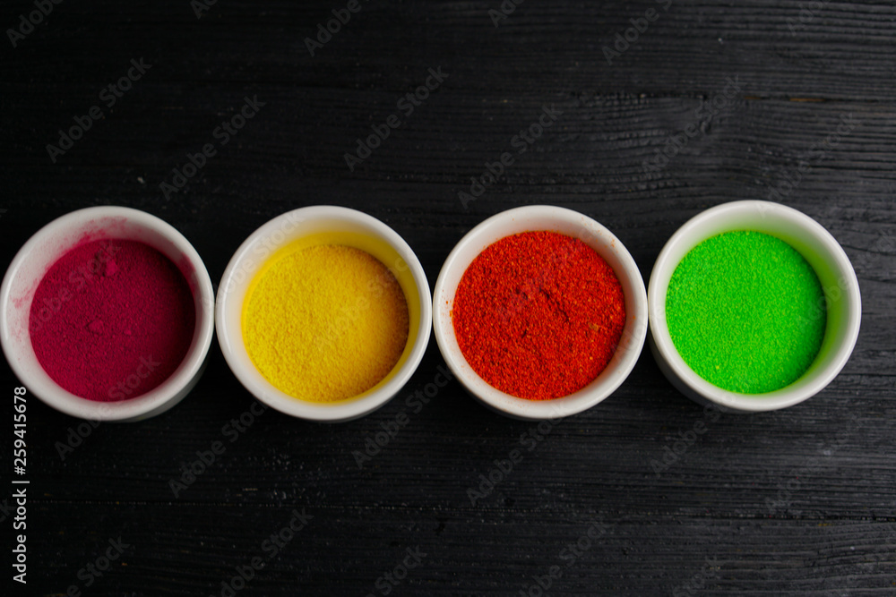 Multicolored bright seasonings in ceramic ware on a wooden background, sea salt and greens Multicolored bright seasonings in ceramic ware on a wooden background, sea salt and greens