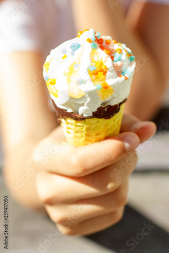 Hand holds ice cream in a waffle cone in summer under the sun. Selective focus