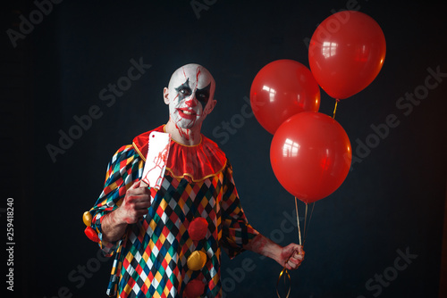 Bloody clown with meat cleaver holds air balloon
