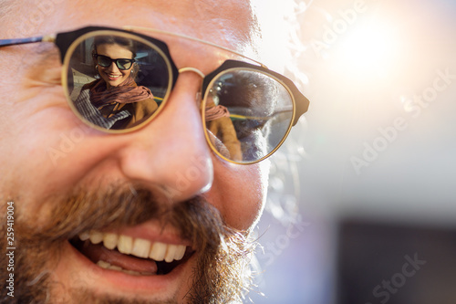 Smiling man in sunglasses with reflection of woman