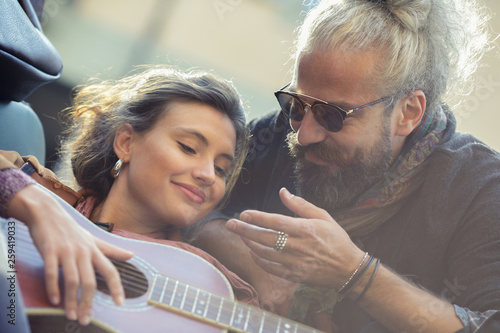 Man looking at woman playing guitar