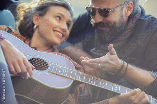 Man looking at woman playing guitar