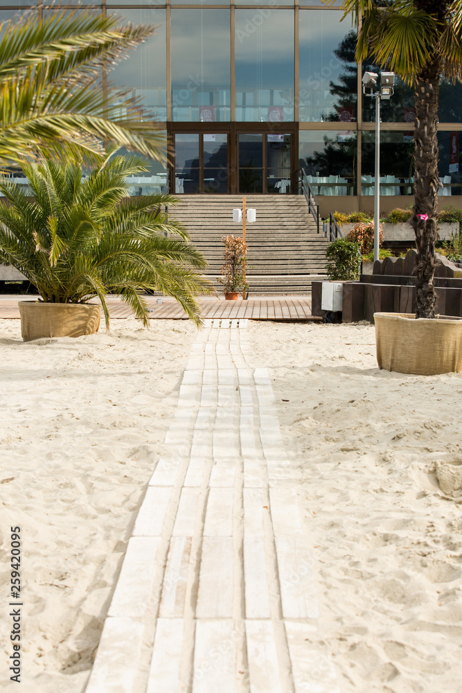 Wooden pathway through beach to modern glass building