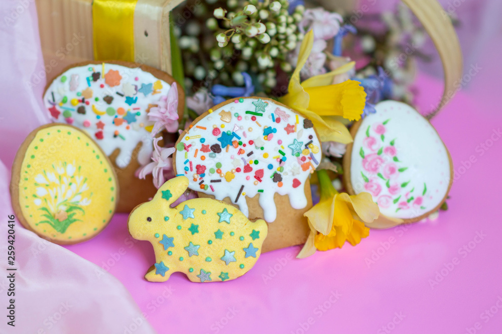 Flat lay Easter treats gingerbread cookies in the form of Easter cake, Easter eggs and rabbits decorated with glaze with spring flowers on a pink background with place for text Flat lay Easter treats gingerbread cookies in the form of Easter cake, Easter eggs and rabbits decorated with glaze with spring flowers on a pink background with place for text