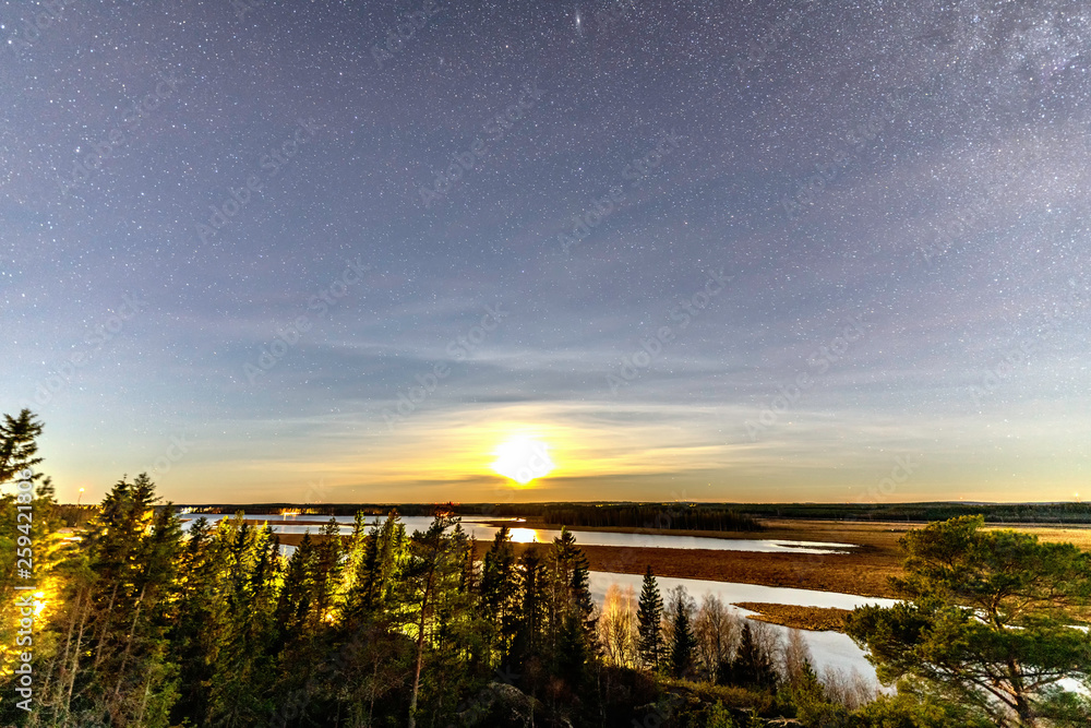 Obraz premium Full moon and stars in clear sky shines over Scandinavian wild forest, lakes, swamps, long exposure night photo, autumn, virgin landscape