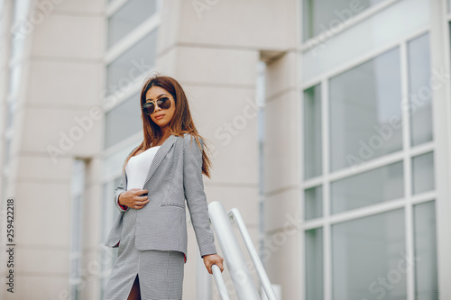 Beautiful businesswoman in a city. Businesswoman in a elegant dress. Lady in a city. Pretty girl with sunglasses