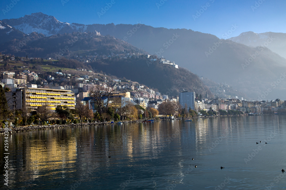 Panorama city of Montreux about of Lake Leman or Lake of Geneva with morning mist over the water surface. At the background are the snow-covered Alps in Montreux, Switzerland