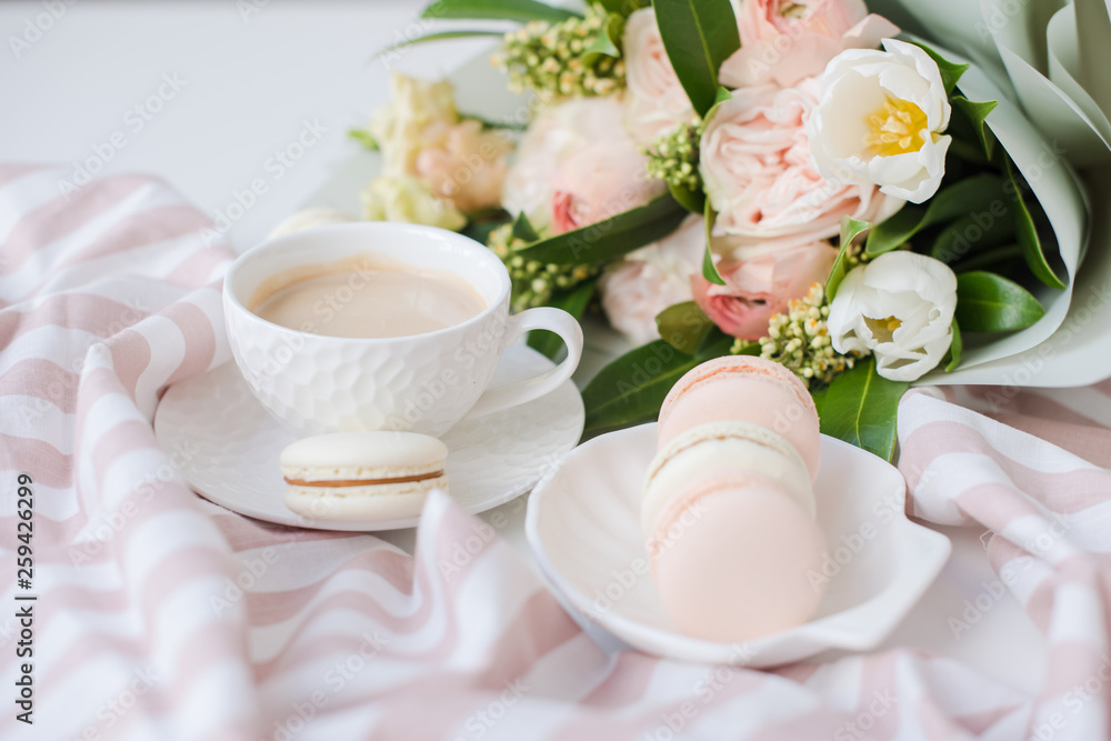 Elegant sweet dessert macarons, cup of coffee and pastel colored beige flowers bouquet Elegant sweet dessert macarons, cup of coffee and pastel colored beige flowers bouquet