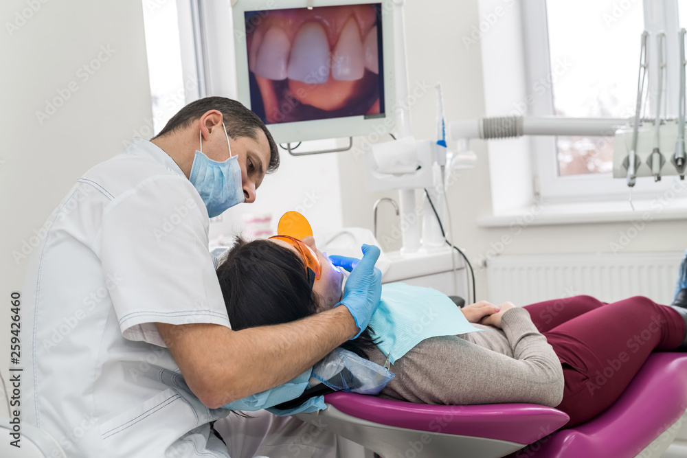 Dentist making whitening to patient in stomatology Dentist making whitening to patient in stomatology