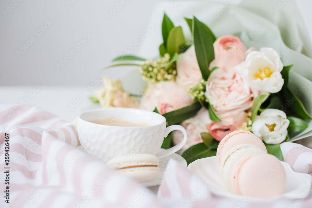 Elegant sweet dessert macarons, cup of coffee and pastel colored beige flowers bouquet Elegant sweet dessert macarons, cup of coffee and pastel colored beige flowers bouquet