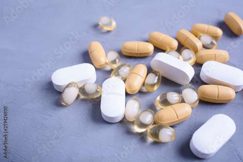 A lot of different pills, vitamins, nutritional supplements on a gray background