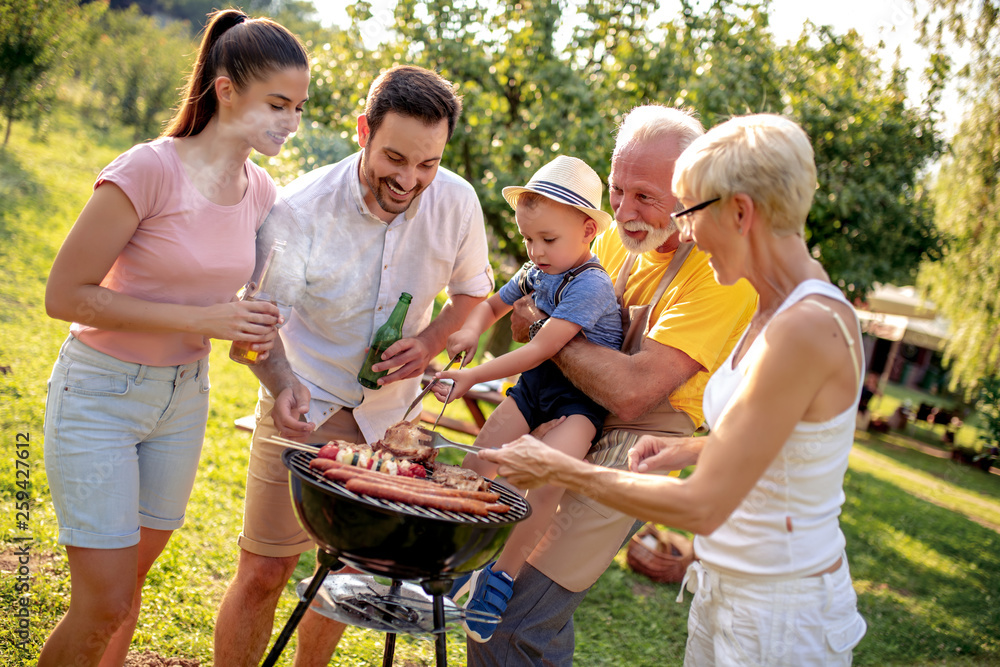 Family having barbecue party around the grill Photos | Adobe Stock