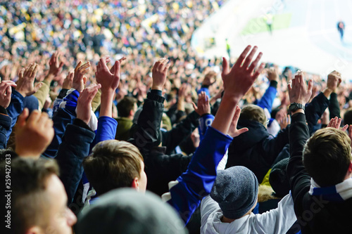 Football fans raising hands, chanting, supporting national team at stadium photo