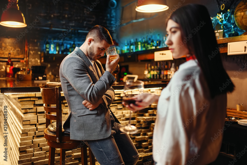 Man lovingly looks on woman at wooden bar counter
