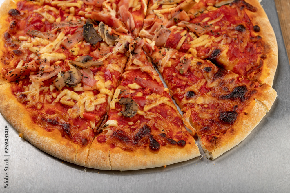 Pizza from the supermarket re-heating in the oven on a wooden table. Fast food prepared in the home kitchen. Pizza from the supermarket re-heating in the oven on a wooden table. Fast food prepared in the home kitchen.