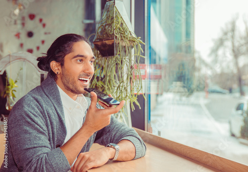 Valokuvatapetti Latin american young adult using voice recognition at phone.