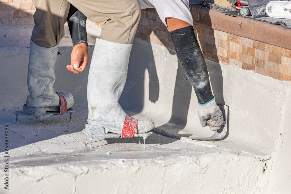 Worker Wearing Spiked Shoes Smoothing Wet Pool Plaster With Trowel Worker Wearing Spiked Shoes Smoothing Wet Pool Plaster With Trowel