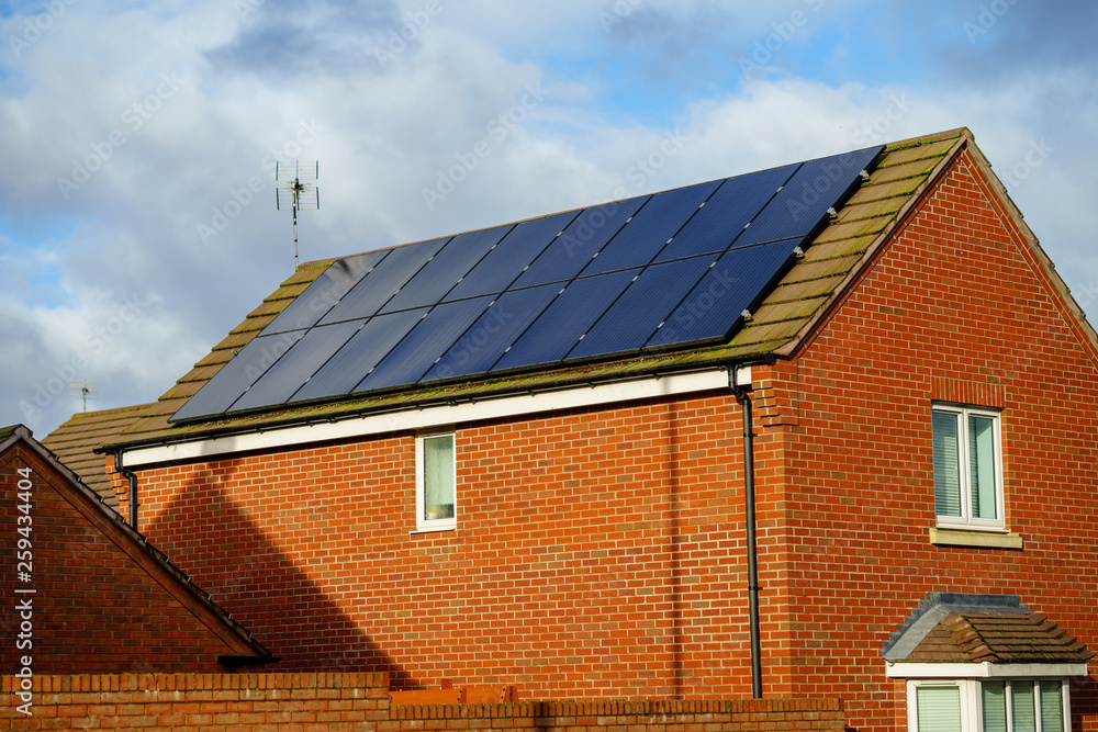 Fototapeta premium Solar photovoltaic panels mounted on a tiled new familiy houses roof, England