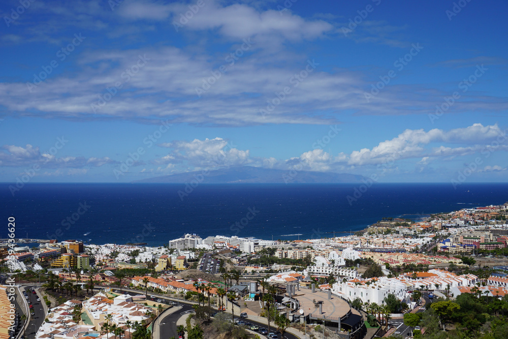 Panoramic view of the ocean, blue sky, clouds, La Gomera island and Costa Adeje. Tenerife, Canary Islands, Spain. Sunny day. Panoramic view of the ocean, blue sky, clouds, La Gomera island and Costa Adeje. Tenerife, Canary Islands, Spain. Sunny day.