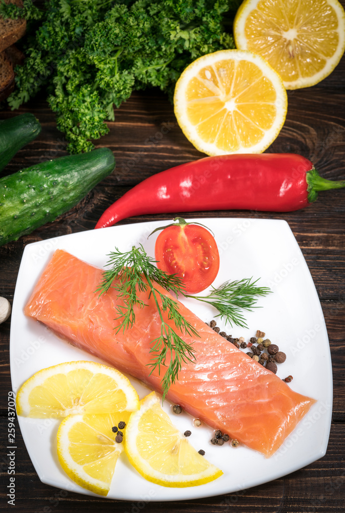 Fresh salmon fish with lemon and salad leaves on wooden table Fresh salmon fish with lemon and salad leaves on wooden table