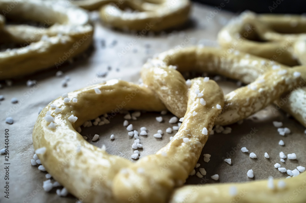 Raw pretzels with coarse salt are placed on a metal tray and are ready for baking in the oven. Traditional food. Oktoberfest. Raw pretzels with coarse salt are placed on a metal tray and are ready for baking in the oven. Traditional food. Oktoberfest.