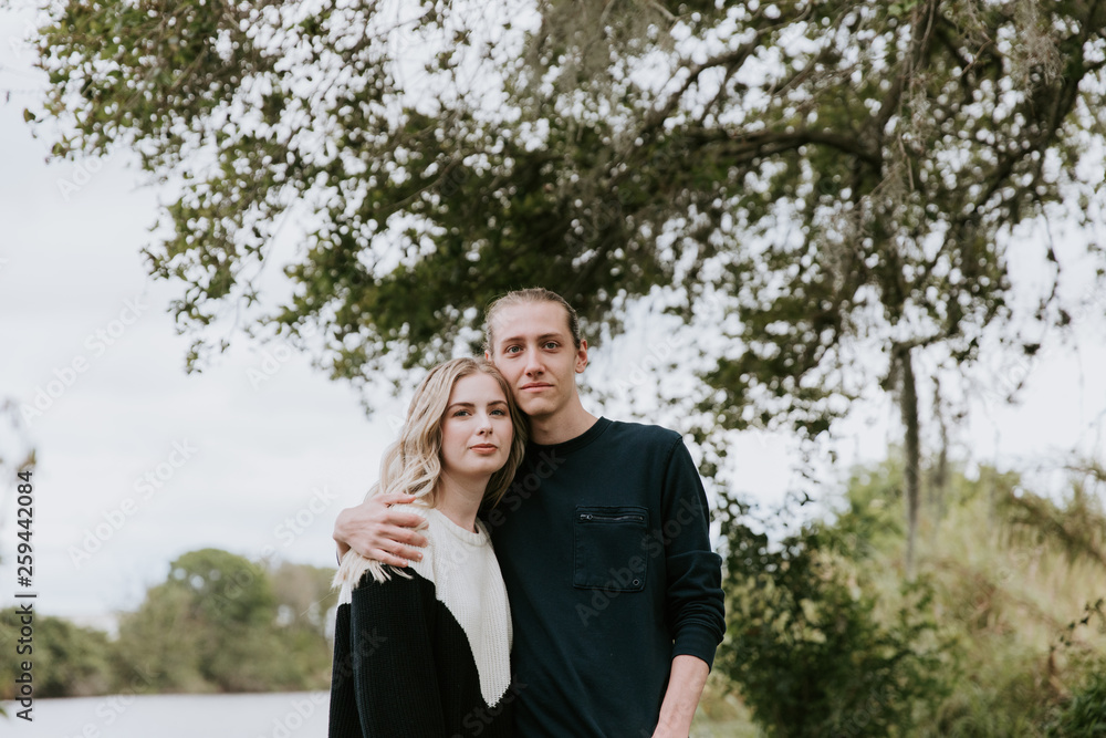 Young Romantic Couple Holding Each Other for Couples Portraits by the Pond Outside in Nature Young Romantic Couple Holding Each Other for Couples Portraits by the Pond Outside in Nature