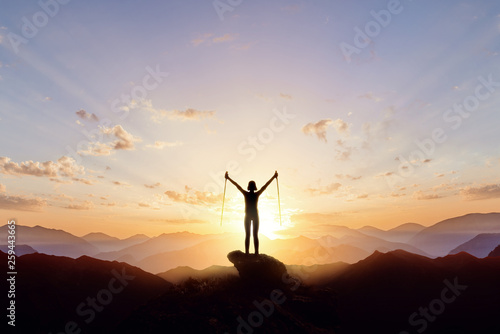 Silhouette of a tourist girl in the mountains against the background of the rising sun