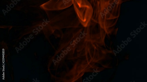 Clouds of fiery red smoke billow rising swirl up, isolated on black background. Cigar smoke blowing to top. Closeup.