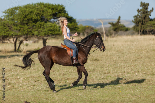 Attractive young blonde woman riding her horse