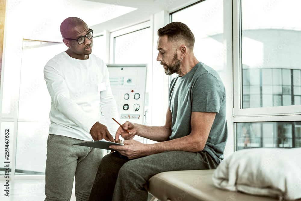 Obraz premium Handsome young therapist pointing at important document