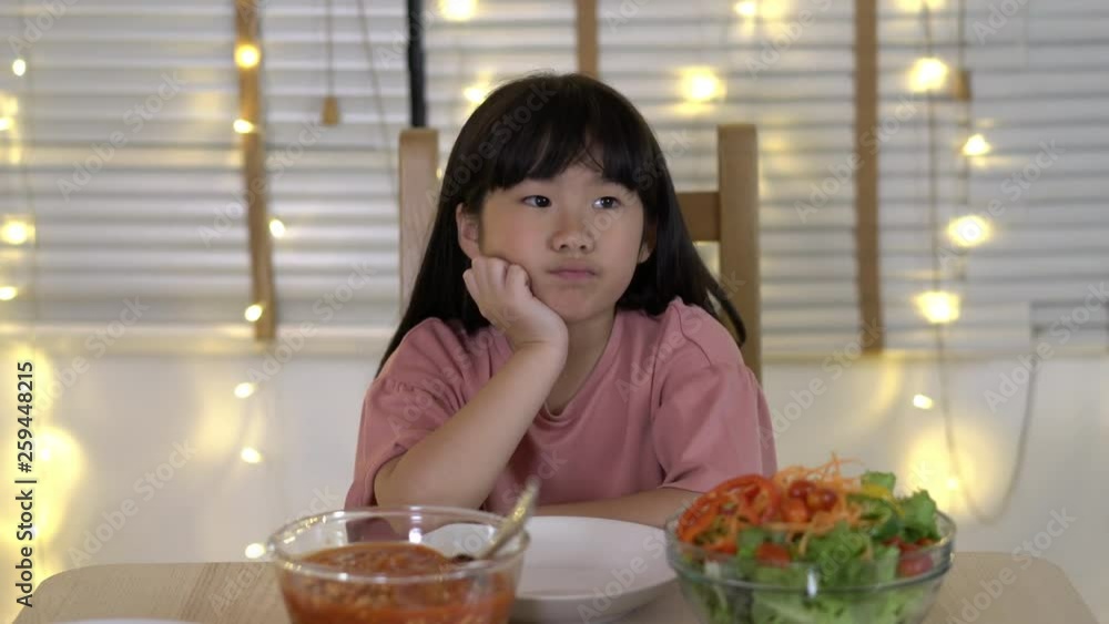 Asian kids girl waiting father and mother coming home birthday party and dinner together. Unhappy family time at home. Concept of lonely, disappointed and sad. Asian kids girl waiting father and mother coming home birthday party and dinner together. Unhappy family time at home. Concept of lonely, disappointed and sad.